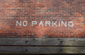 No parking painted on brick wall in white letters