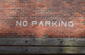 No parking painted on brick wall in white letters