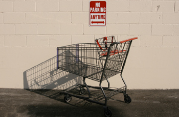 No parking sign on wall in front of shopping cart 